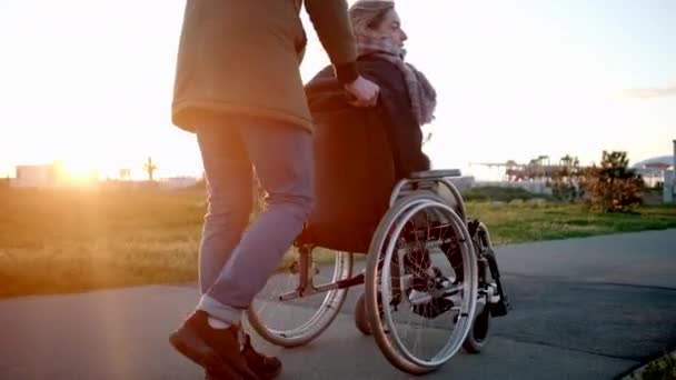 L'homme prudent roule chariot invalide avec la femme dans le jardin, soulevant des roues — Video