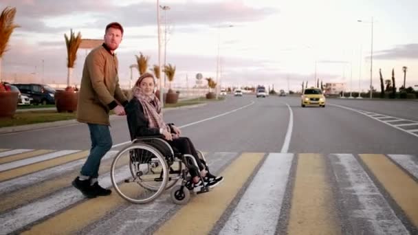 El hombre está eliminando a la mujer discapacitada en el transporte sobre el cruce peatonal en la ciudad — Vídeos de Stock