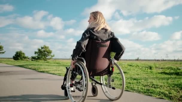 Adulti disabili donna sta guidando la sedia a rotelle nella zona del parco in giornata di sole — Video Stock