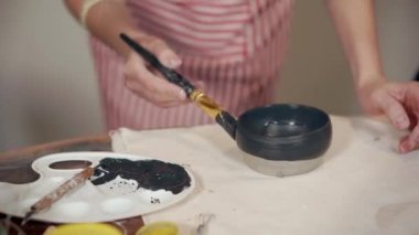 Sınıfta seramik bardağını süsleyen kadın..