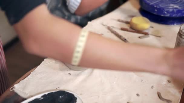 Kadın sanatçı atölye masasında siyah boya ile yeni kil fincan boyama olduğunu — Stok video