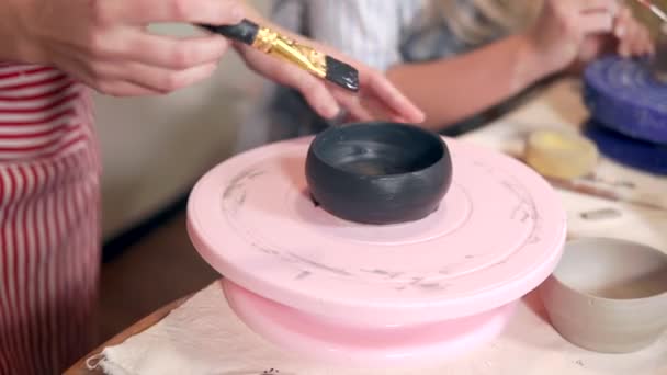 Mujer está cubriendo por tinte negro una taza de cerámica en el taller — Vídeos de Stock