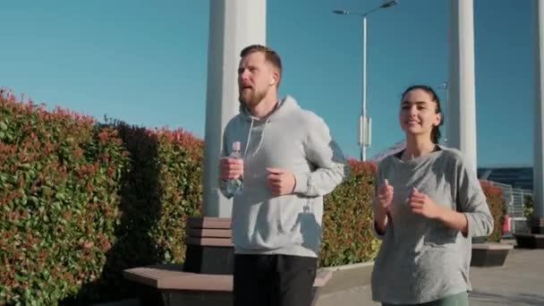 Para jest jogging w parku w mieście w słoneczny poranek, widok z przodu — Wideo stockowe