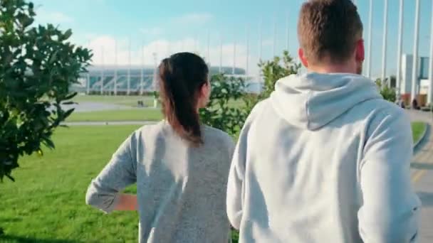 El hombre y la mujer están corriendo en el parque juntos, vista trasera — Vídeo de stock