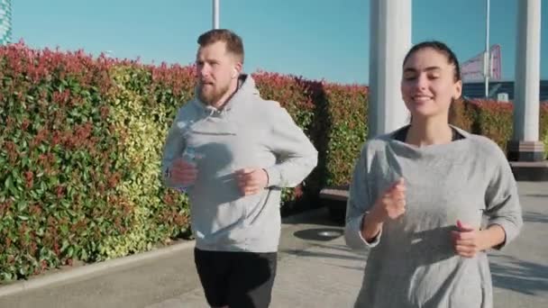 Jeune homme et femme font du jogging ensemble dans la matinée ensoleillée en plein air — Video