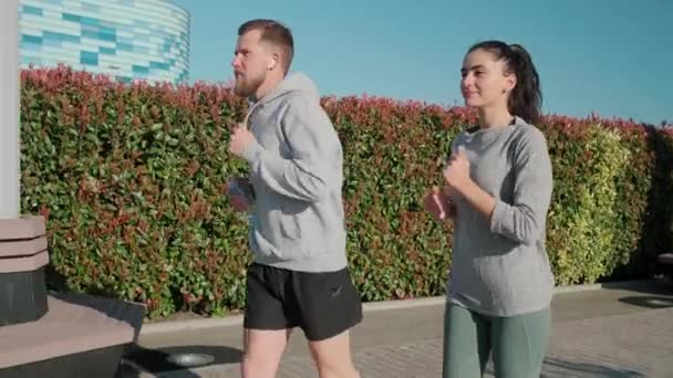 Desportos masculinos e femininos fazem corrida matinal no jardim da cidade — Vídeo de Stock