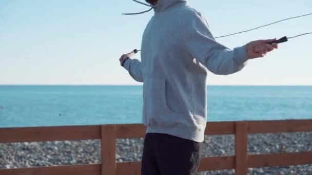 Sportsman está saltando la cuerda en un día soleado cerca del mar — Vídeos de Stock