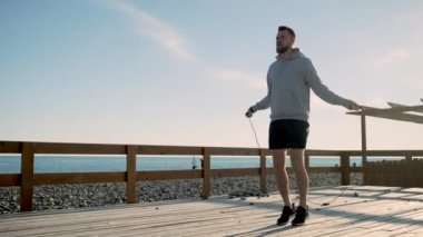 Yakışıklı genç adam, deniz kıyısında ip atlama, çalışıyor