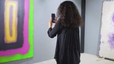 Sanat galerisinin kadın konuğu akıllı telefonla fotoğraf çekiyor