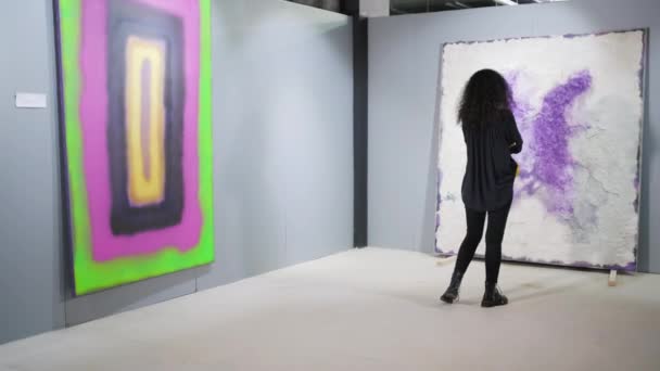 孤独的黑发女人正在艺术画廊里看抽象图片 — 图库视频影像