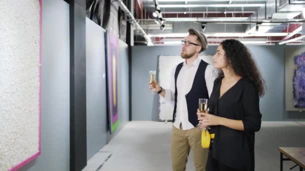 Mężczyzna i kobieta pije szampana i oglądanie obrazu w nowoczesnej galerii sztuki — Wideo stockowe