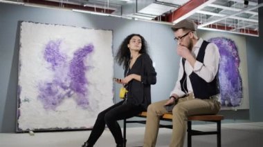 İki sanatsever galeride modern sanat eserlerinin tadını çıkarıyor ve ses rehberini dinliyor