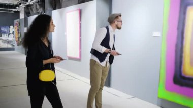 Modern resim sergisi ziyaretçileri ses rehberi tarafından yorum dinliyor