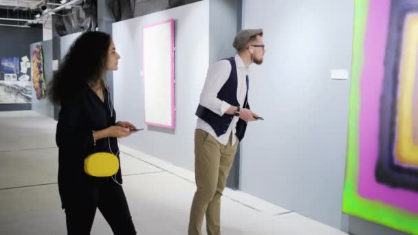 Visitantes da exposição de pintura moderna estão ouvindo comentários por guia de áudio — Vídeo de Stock