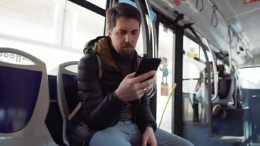 Adam otobüse biniyor ve akıllı telefonun ekranına bakıyor.