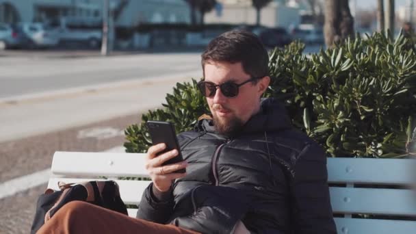 Ember van szemöldök mellett smartphone ülő kint — Stock videók