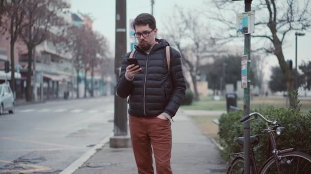 Man is waiting bus on station and using smartphone — Stock Video