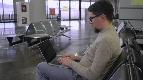 男子在机场大厅的笔记本电脑键盘上打字 — 图库视频影像