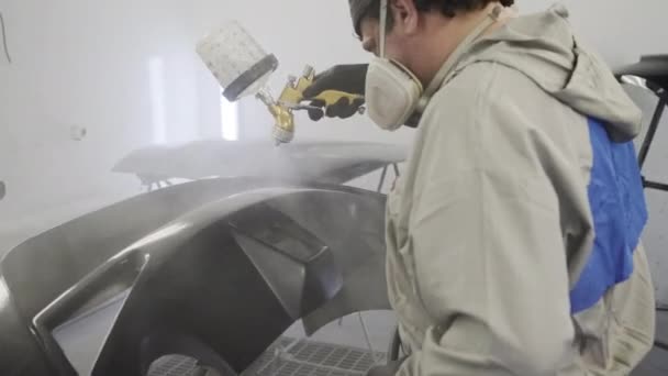 Malarz pracuje w komorze lakierowania centrum serwisowego samochodów, farbowanie detali — Wideo stockowe