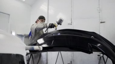 İşçi boya püskürtme kabini içinde otomobil tampon boyama.