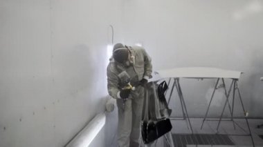 Ressam araba servis odasında oto detay üzerinde siyah boya uyguluyor