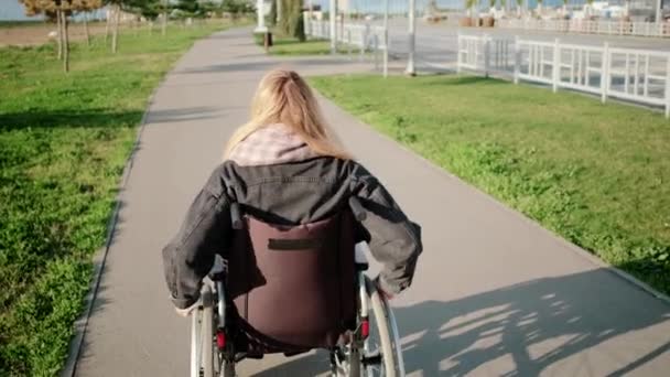 Femme en fauteuil roulant en promenade en plein air — Video