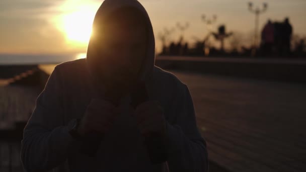 Boxer man is fighting in air with dumbbells in hands, shadow in dusk time — Stock Video