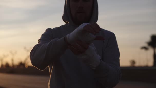 Fighter emballe les mains avec un bandage élastique au crépuscule avant l'entraînement — Video