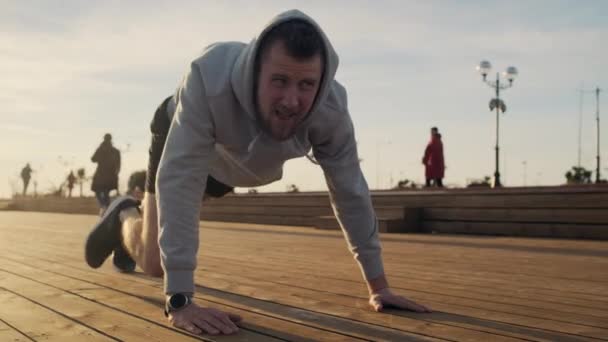 Unavený muž provádí fyzická cvičení v parním areálu města v době západu slunce — Stock video