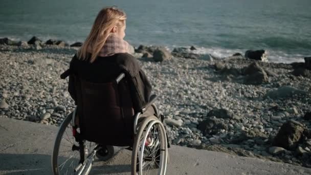 Инвалидная женщина в инвалидной коляске одна с морем — стоковое видео
