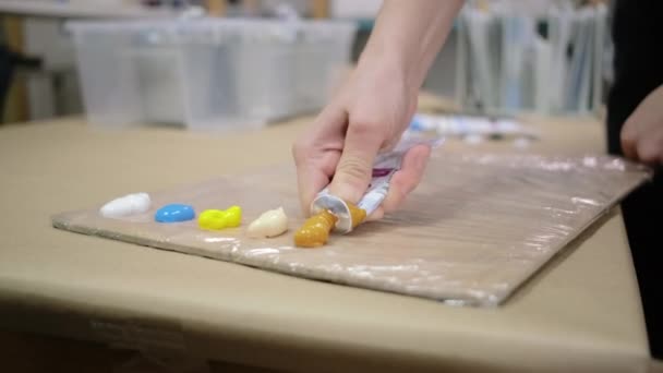 Художник выжимает красители из трубок в мастерской, крупным планом — стоковое видео