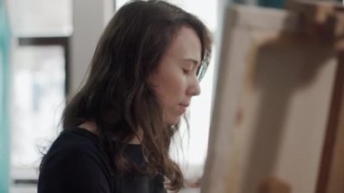 İlham kadın fırça ile bir resim boyama, şüskül önünde oturuyor