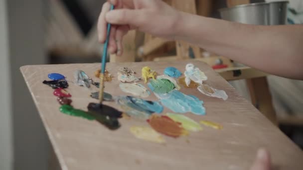 Artista está mezclando colores en la paleta y aplicando sobre lienzo — Vídeos de Stock