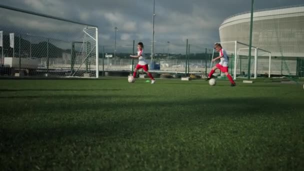 Team av små pojkar är utbildning på fotbollsplan, dribblingar bollar — Stockvideo