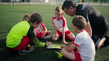 Küçük çocuklar ve antrenör futbol takımı bir taktik tartışıyor