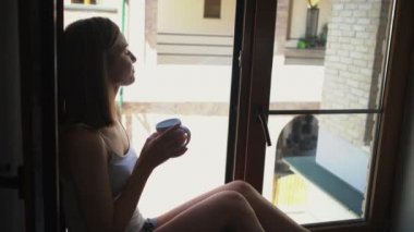 bayan siluet kahve fincanı ile pencere üzerinde oturur