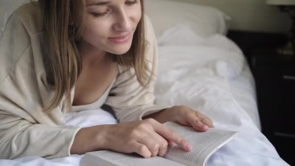 Blonde girl reads book running finger on sheets — Stock Video