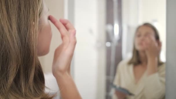 Young woman in bathrobe puts eye shadows at mirror — Stock Video