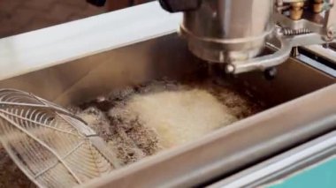 Hamur derin fritöz kaynar yağ içinde pişirme, aşçı karıştırıyor