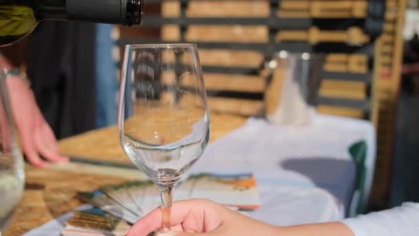 Person häller vitt vin i högt glas under provningen — Stockvideo