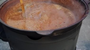 aşçı kepçe ile geleneksel Amerikan chowder karıştırır