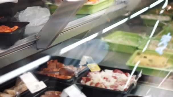 Продавец кладет маринованное мясо в упаковку в супермаркет — стоковое видео