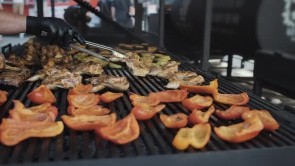 Cozinheiro vira fatias de carne com pinças perto de legumes — Vídeo de Stock