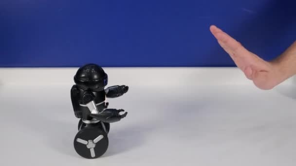 Liten robot leksak på hjul kör bort från mänsklig hand — Stockvideo