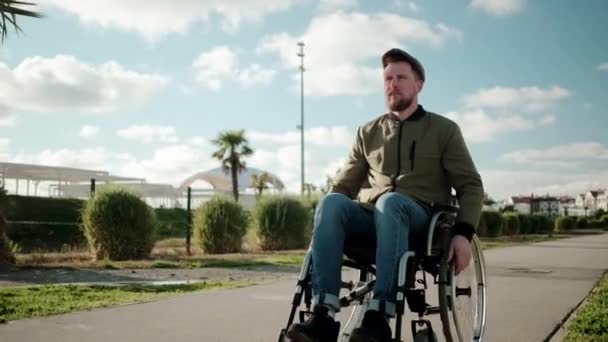 Человек с параличом мышц ног сидит в инвалидной коляске и едет верхом — стоковое видео