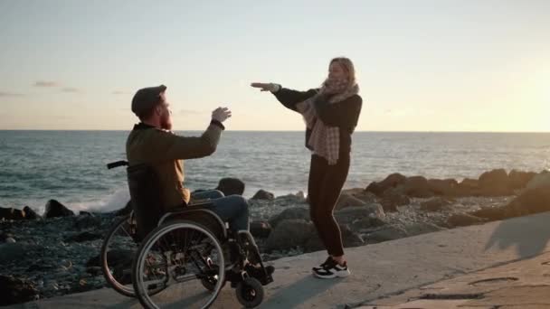 Cheerful disabled man and woman are having fun and dancing on sea embankment — Stock Video