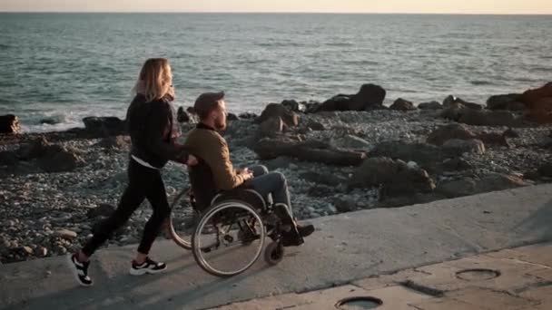 Ragazza con ragazzo handicappato a piedi lungo il mare — Video Stock