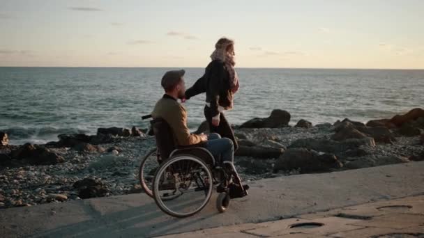 Disabled man and his healthy girlfriend are having fun on sea shore, dancing — Stock Video