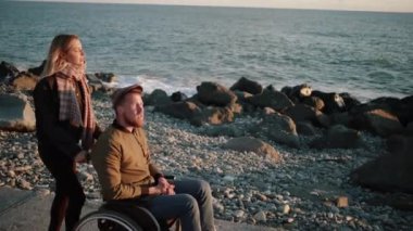 Kız arkadaşı ile engelli adam deniz kenarında yürüyüş