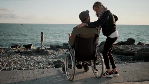 Woman is embracing her beloved disabled husband on sea shore — Stock Video